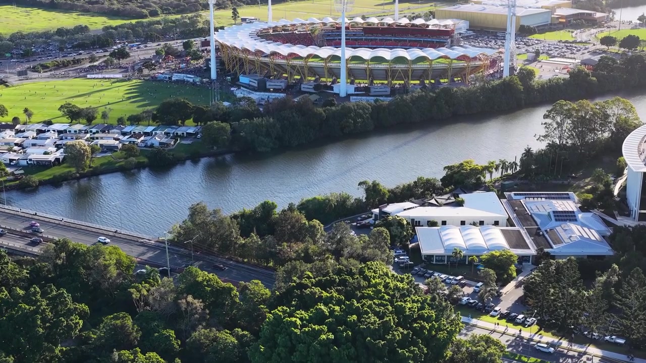 Ripresa aerea con drone in panoramica su una grande arena sportiva, un fiume e un lussureggiante parco verde