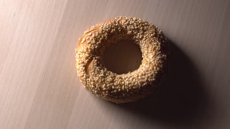 fresh bagels with sesame seeds in rotation. on wooden cutting board. extreme closeup.