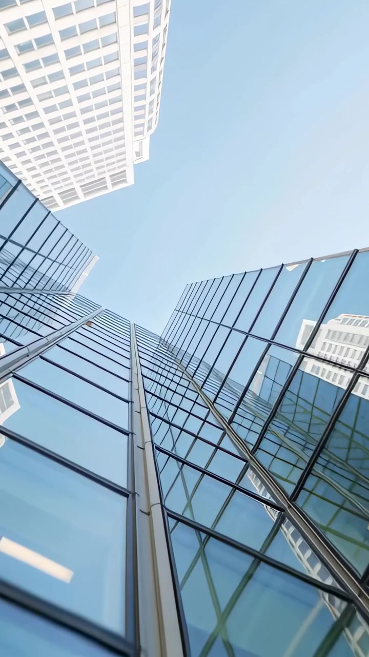 Video vertical: Cámara inclinándose para mostrar una torre de cristal en el centro, revelando los parteluces y el cielo azul.