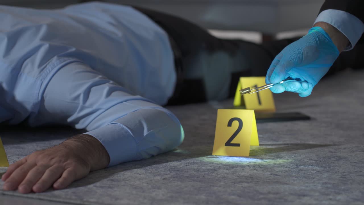 Forensic expert examining shell casing with tweezers at crime scene investigation.