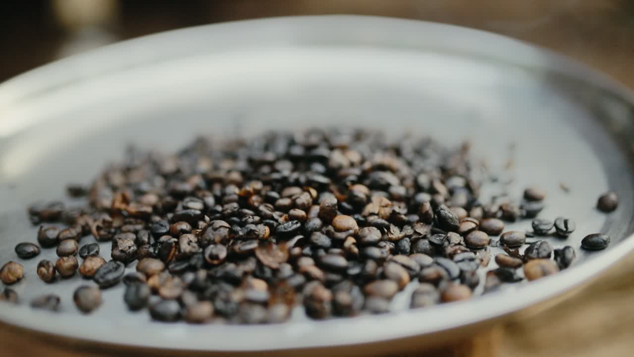 Shallow focus of dark coffee beans being roasted on metal plate