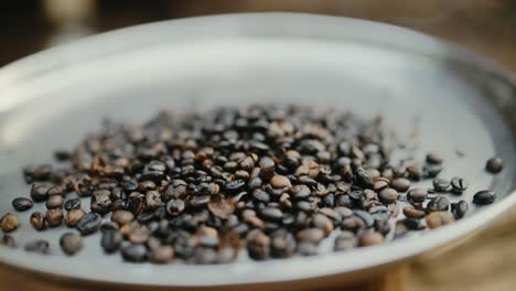 shallow focus of dark coffee beans being roasted on metal plate