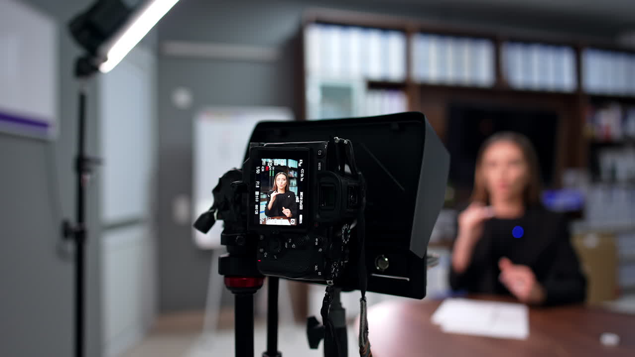Active enthusiastic female with brunette long hair talks to camera gesturing her hands. Creation of content for a modern blog. Blurred backdrop.
