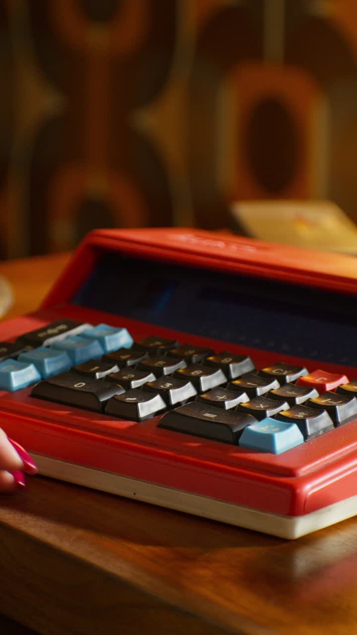 Woman using a vintage red calculator on a wooden table