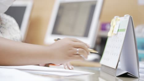 female hand planning working days with calendar at office