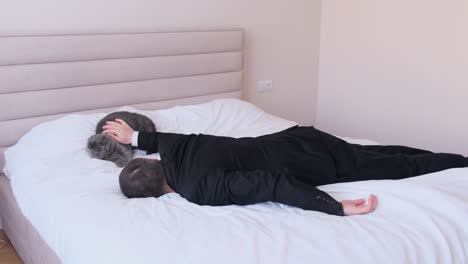 Tired Business Man Stroking a Kitten Lying in Bed. Tired business man stroking a kitten lying in bed. The man went to bed without undressing. End of working day