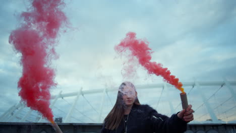 girl standing on city street with smoke grenades. hipster posing at camera