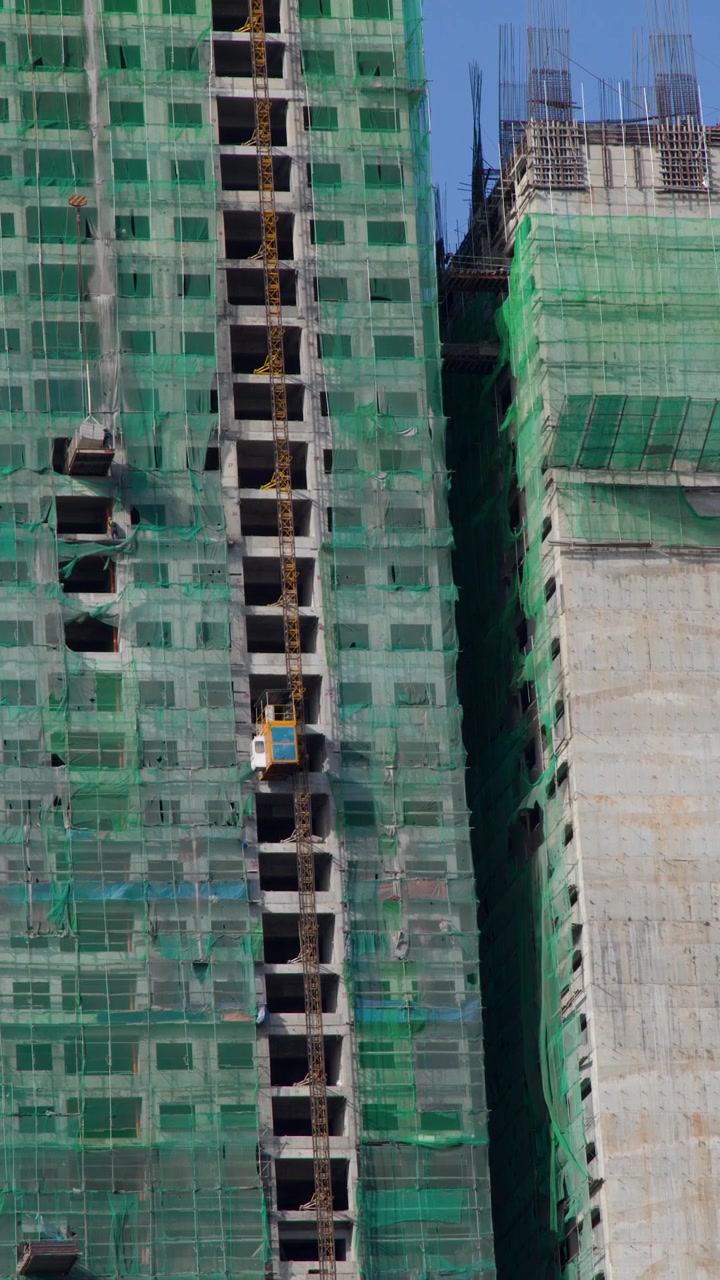 Um edifício de concreto em construção em Manila apresenta rede de segurança verde e elevadores em movimento