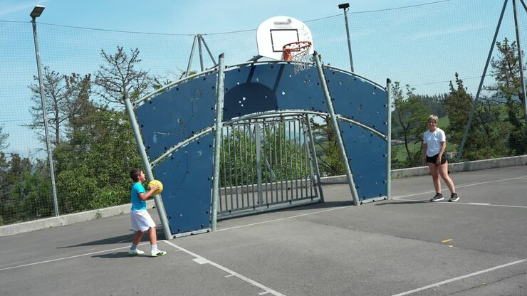 Donna e ragazzo giocano a basket in un campo all'aperto