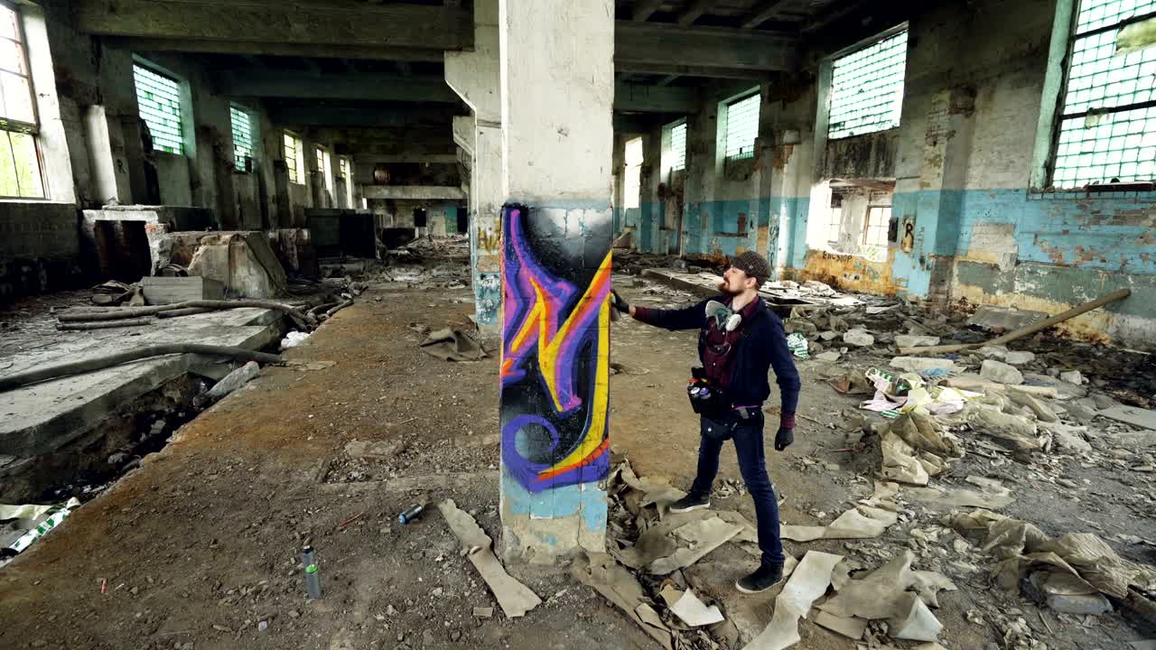 fotografía de alto ángulo de un joven artista urbano decorando una columna alta en un antiguo edificio dañado con una imagen abstracta. arte moderno, pintor callejero, creatividad y concepto de personas.