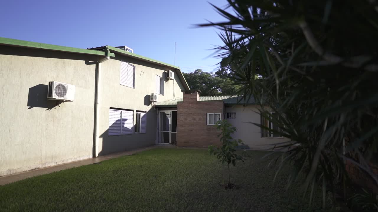 Exterior view of house courtyard with air conditioning units and green lawn at daytime.