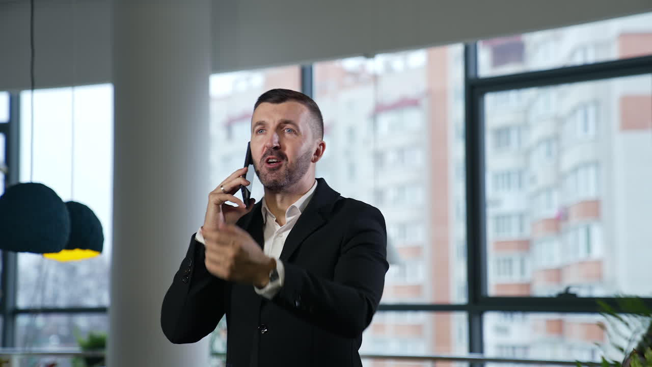 Confident Caucasian middle-aged businessman having conversation over smartphone. Man speaking and pointing forward with his hand. Blurred background.