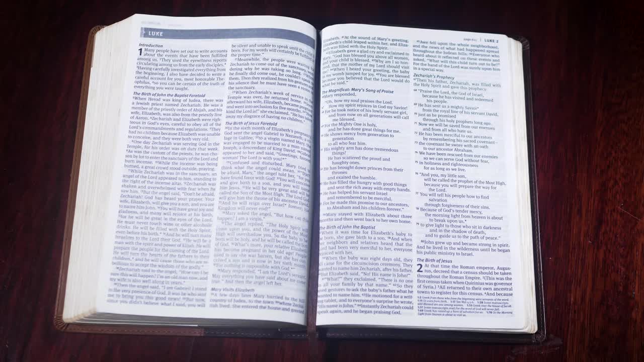 Záběr shora na bibli v kožené vazbě otevíranou na knihu Lukášovu na dřevěném stole.