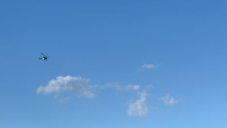 Folgender-Grün-weißer-Hubschrauber-Fliegt-Tagsüber-Durch-Blauen-Himmel-Mit-Wolken