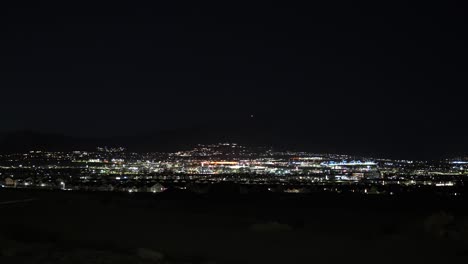 Luces-De-La-Ciudad-De-Un-Pueblo-Distante-En-Un-Valle-Debajo-De-Las-Montañas-En-La-Noche