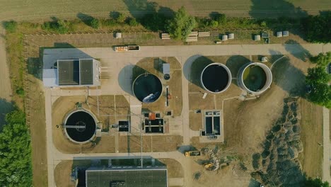 overhead drone footage of comprehensive layout of a wastewater treatment facility, featuring circular tanks and filtration systems essential for water purification and management