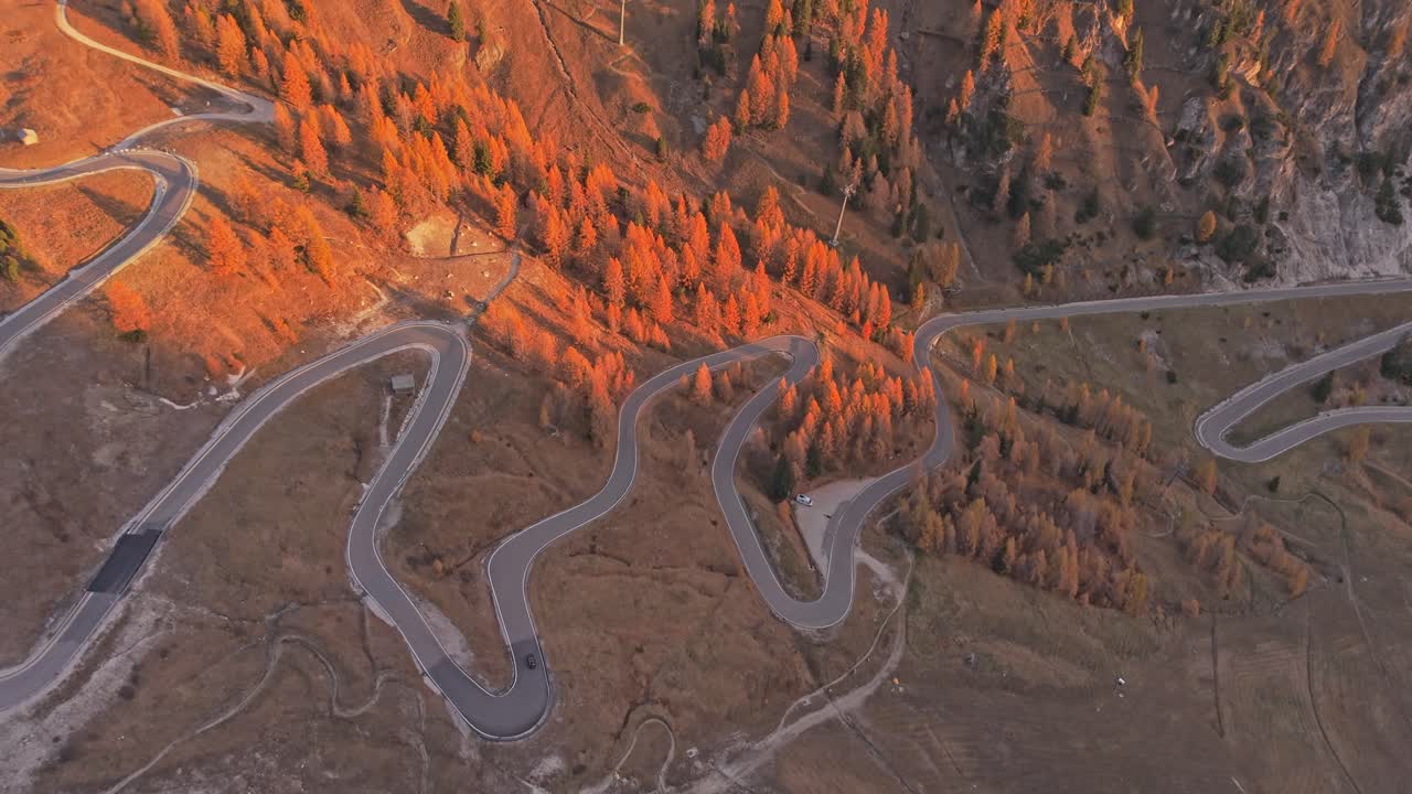 Sunrise drone shot of vehicles crossing Gardena Pass road in the Alps