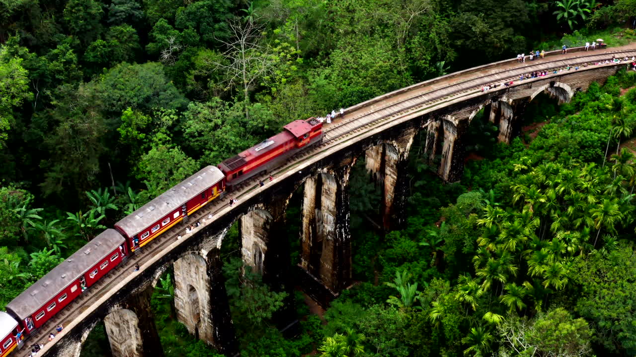 Un drone cattura una vista ravvicinata del ponte ferroviario ad arco di Ella, Sri Lanka, circondato da una fitta vegetazione verde
