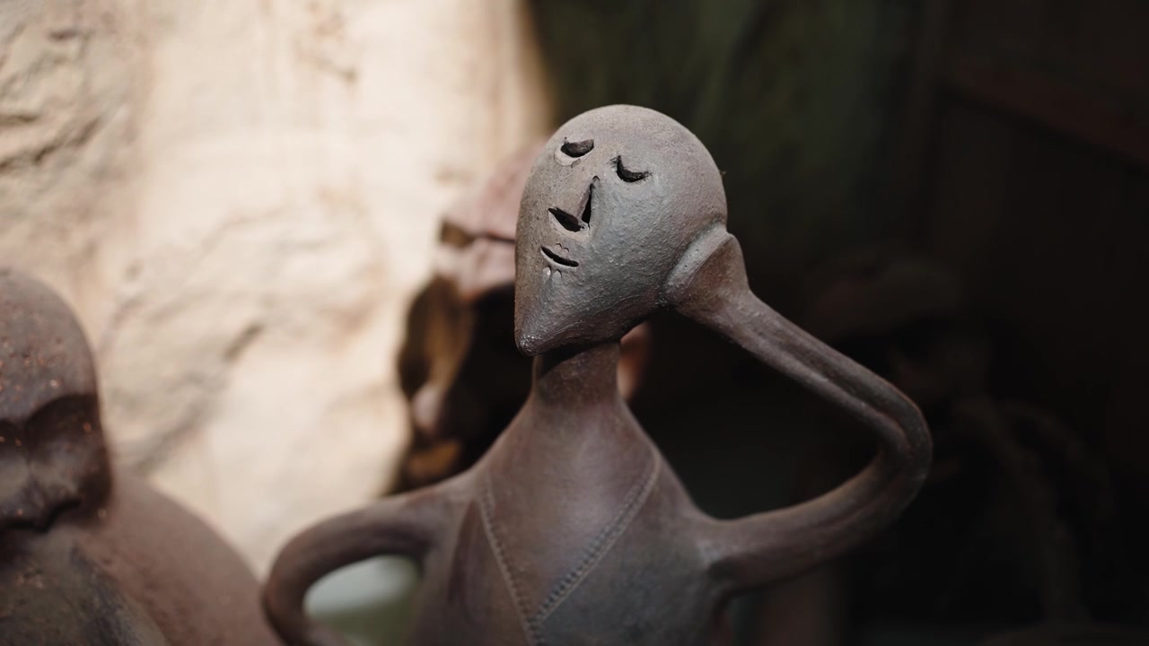 Close up of a dark, rustic tribal sculpture, representing a stylized figure with closed eyes, meditating in a serene atmosphere