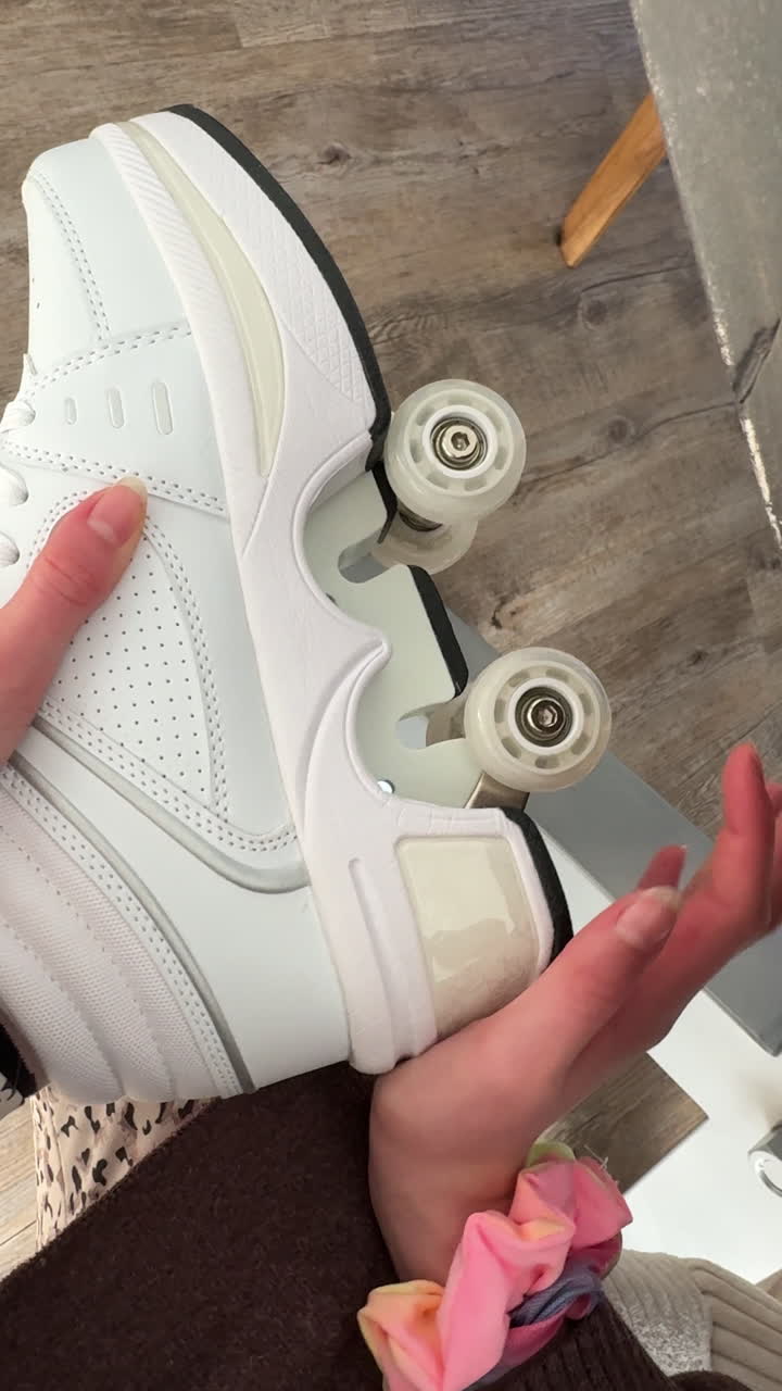 Vertical UGC style clip of child hands opening retractable wheels in sneakers. Close view of roller wheel mechanism inside casual shoes on wooden floor