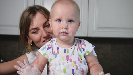 madre joven y su hijo pequeño preparando masa en la mesa. bebé pequeño mirando a la cámara. tiempo en familia, divirtiéndose
