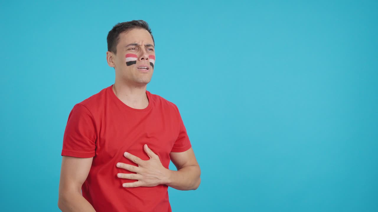 Nervous man cheering for Egypt during a match looking away