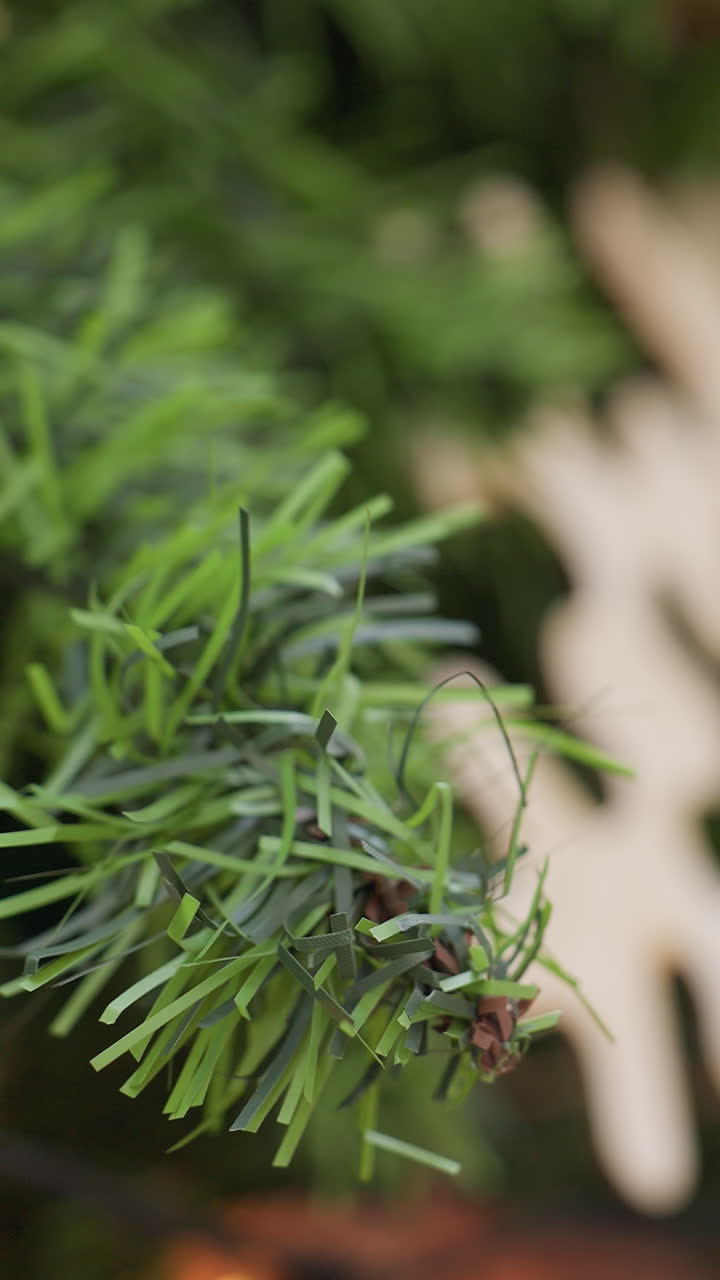 Close-up hand view of lady touching decorative Christmas tree with affection, festive decorations, warm lights, and holiday ornaments in background