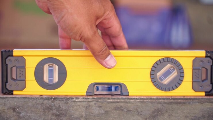 hand checking floor level with spirit level tool, construction measurement, building and precision work concept.