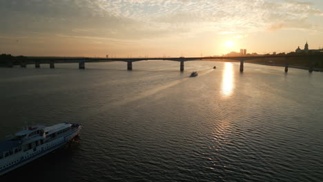 sunset over a river with boats and city bridge