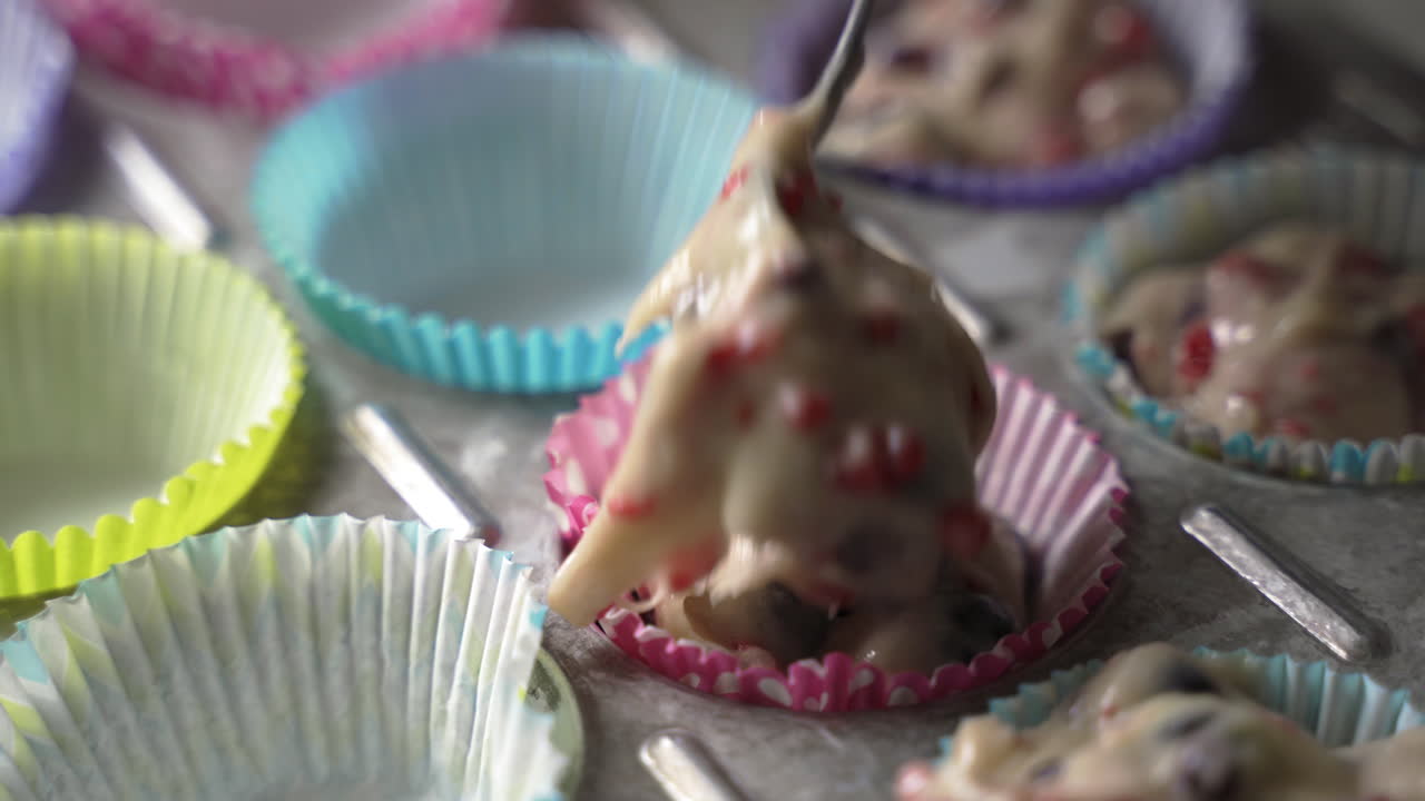 sacar la masa de panecillos con fruta sabrosa en envoltorios coloridos en una bandeja de metal para hornear de cerca