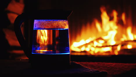 el agua hierve en un hervidor eléctrico retroiluminado un fuego en el fondo arde en el fondo