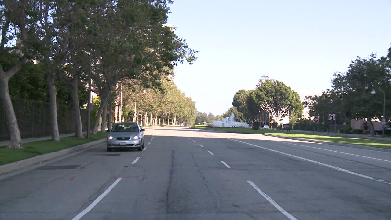 뒷창 4를 통해 보이는 센추리 시티 로스앤젤레스의 거리를 따라 자동차가 이동합니다.