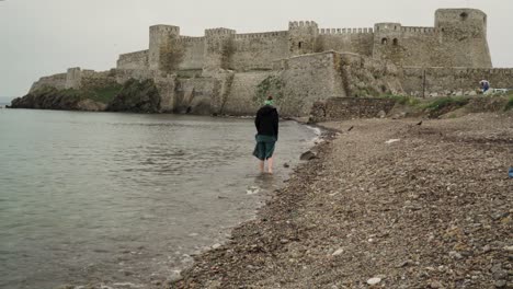 a woman hardly trying to walk on the pebbles on the rocky seaside