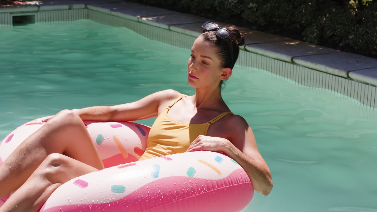 Relaxing in pool, woman enjoying sunny day on colorful inflatable float