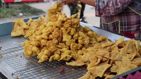 persona organizando y embolsando bocadillos fritos en un puesto