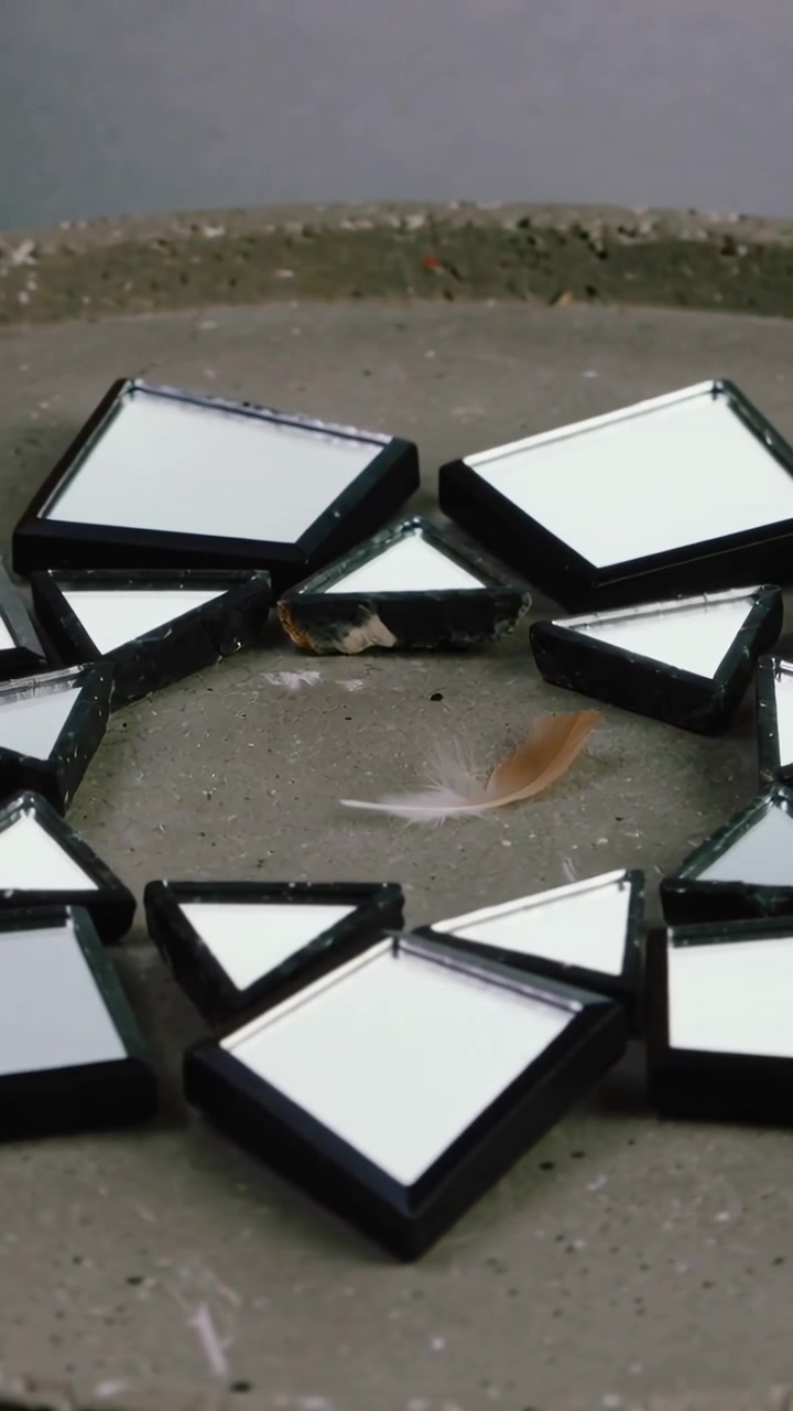 Vertical video: Shifting camera upward and closer revealing mirrors and feather on concrete tray