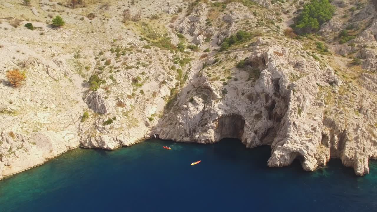 People kayaking in sea, rocks and green nature