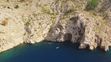 People-kayaking-in-sea,-rocks-and-green-nature