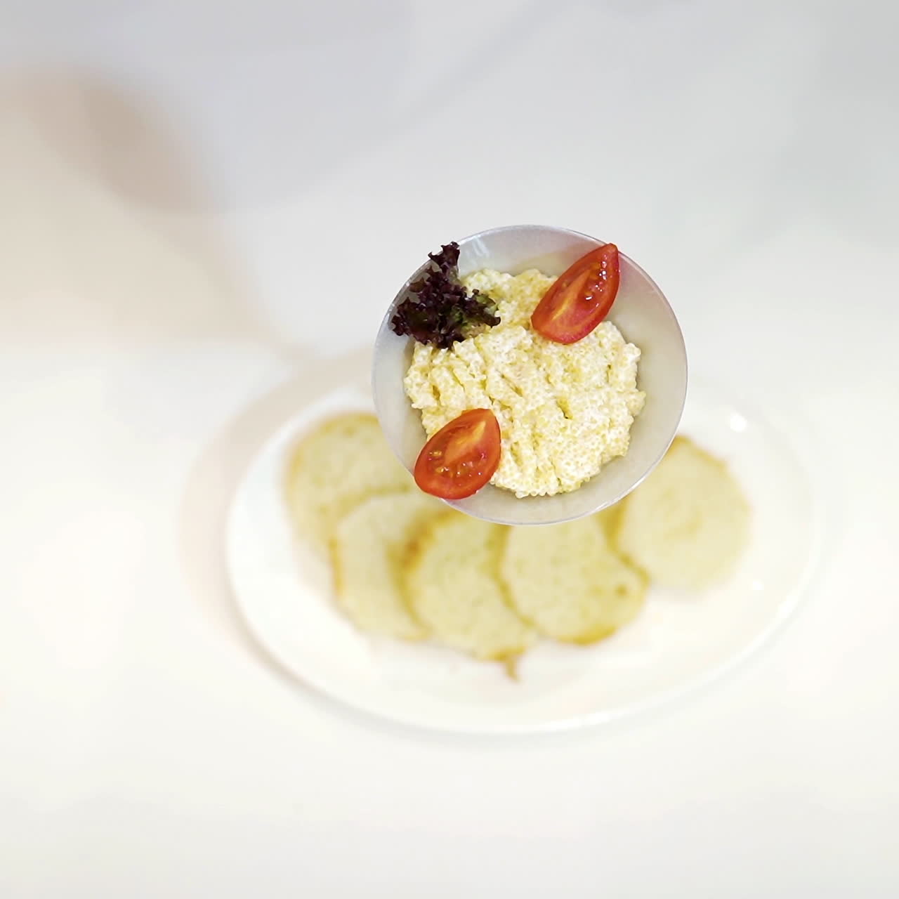 Hand in white glove holding kitchen tongs and decorating tasty dish with vegetables. Delicious food on plates for special day over the white tablecloth. Close-up