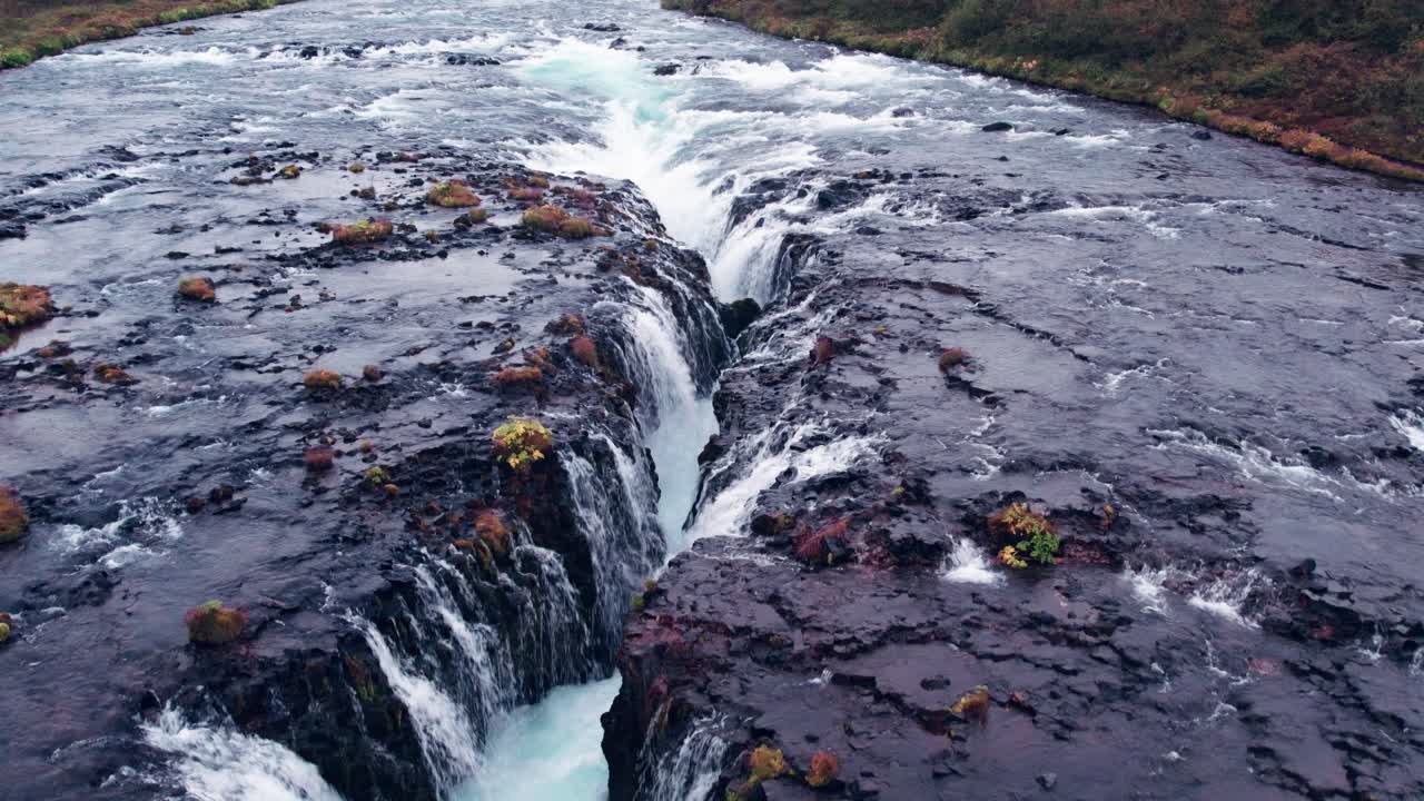 aerial: sobrevuelo cercano de la cascada de bruarfoss en el sur de islandia que es muy pintoresca con la hermosa cascada azul de caídas en la piscina de inmersión debajo