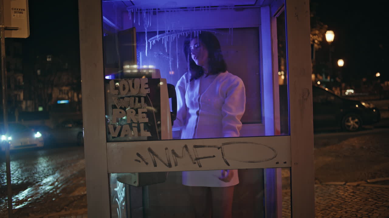 Seductive model posing neon phone cabin portrait. Happy woman looking camera