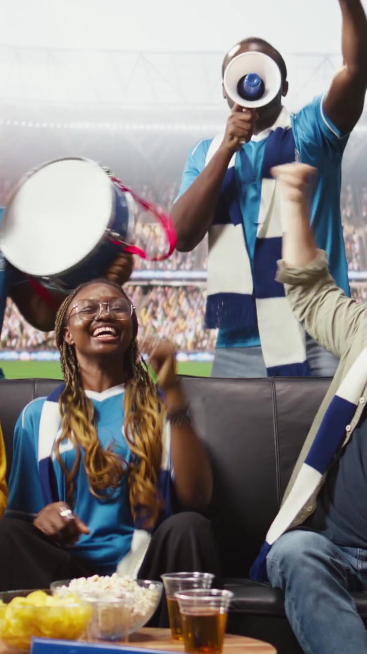 Video vertical: Aficionados al fútbol en casa haciendo mucho ruido con megáfono y tambor.