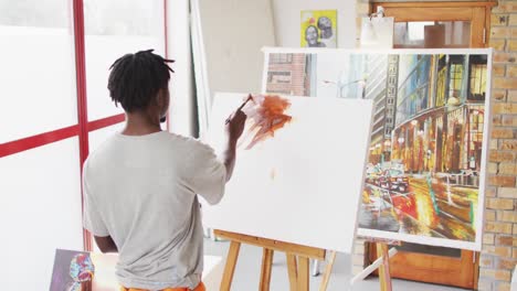 african american male painter painting on canvas in artist studio