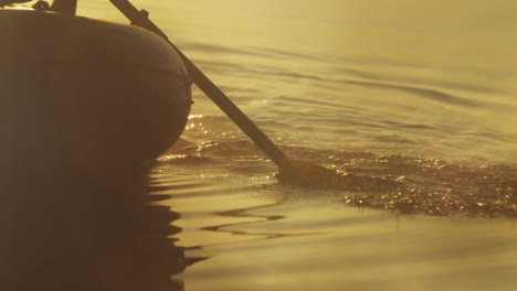 Close-up-view-of-oars-moving-in-the-water-of-a-lake-on-a-cloudy-morning