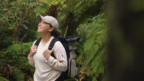 slow motion shot of a happy female hiker walking through a dense green forest