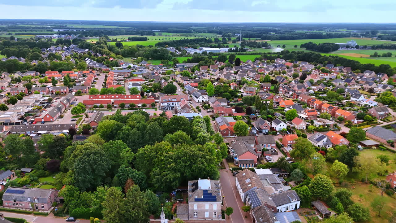 Luftfoto af en frodig grøn park i en hollandsk by. Forhøjet billede, der viser en tæt klynge af høje grønne træer omgivet af beboelseshuse og landsbygader.