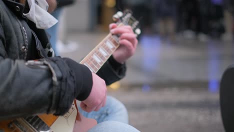 close-up of a male music lover playing the guitar in a crowded city. guitarist’s street concert