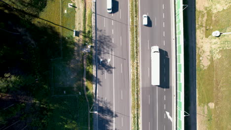 drone tracking pan top down above multi lane highway half covered by tree shadow