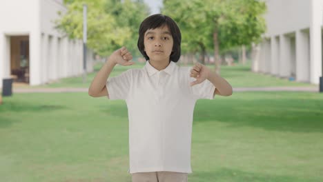 disappointed indian boy showing thumbs down in park