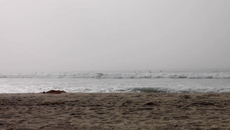 surfistas en venice beach california mientras el sol intenta atravesar la gruesa capa marina